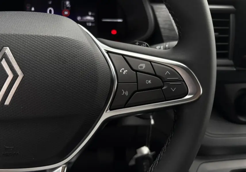 Gros plan sur le volant cuir multifonction du Renault Trafic Fourgon 2025, boutons de commande à droite visibles.