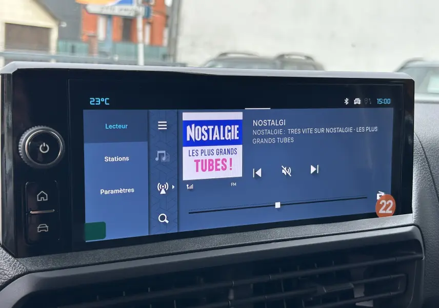 Écran tactile central du tableau de bord du Citroën Jumpy gris titane, affichant la radio Nostalgie à 15h00.