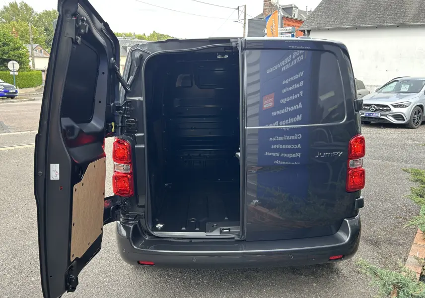 Vue arrière du Citroën Jumpy gris titane 2025 avec porte gauche ouverte révélant l'espace de chargement vide.