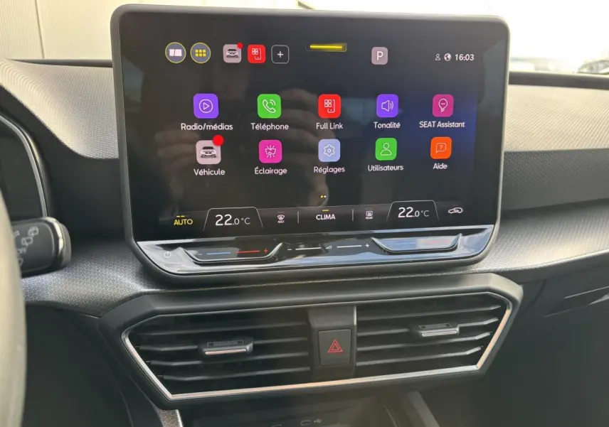 Écran tactile central du tableau de bord de la SEAT LEON 2025 avec interface connectée et commandes climatiques.