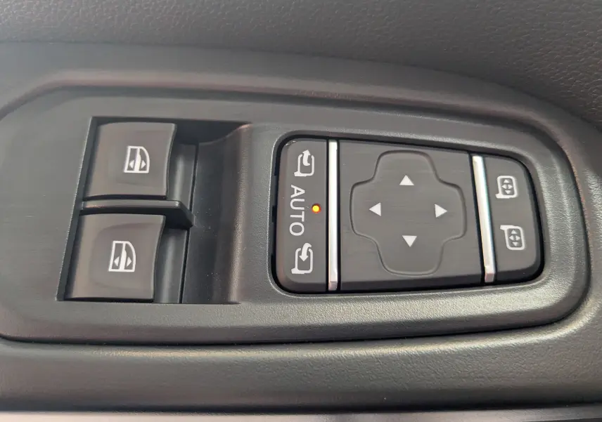 Gros plan sur les commandes de réglage des rétroviseurs et des vitres électriques côté conducteur du Renault Trafic gris comète.