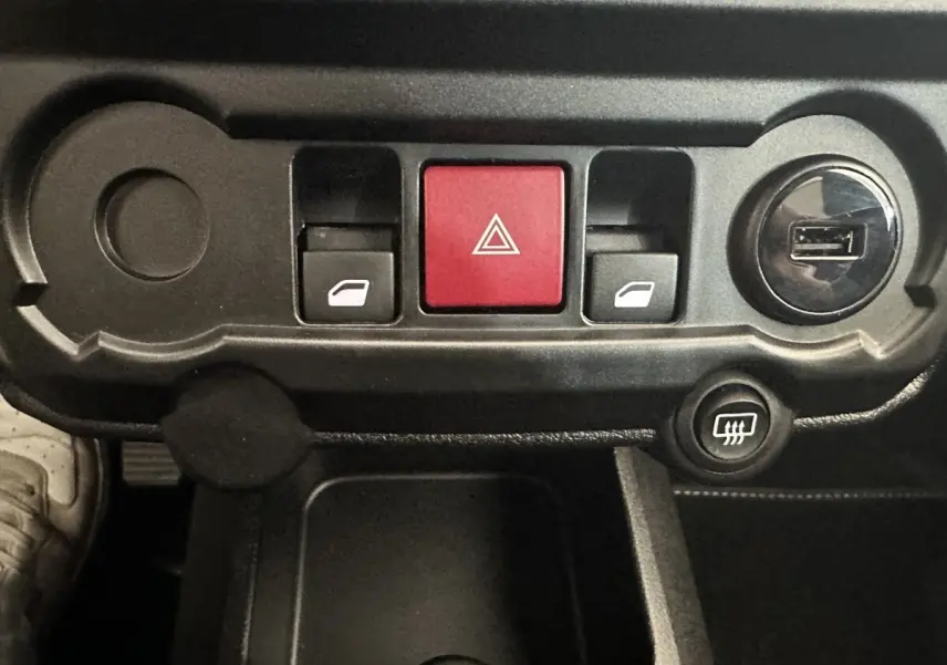 Gros plan sur la console centrale noire de l'AIXAM AMBITION 0.5 CROSSOVER PREMIUM avec boutons de vitres et alerte.