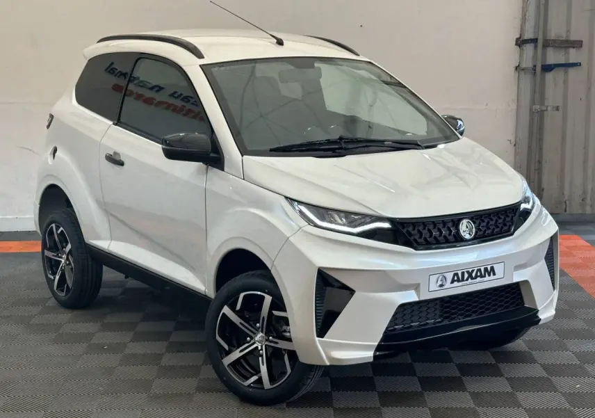 Vue 3/4 avant droit d'une Aixam Ambition 0.5 Crossover Premium blanche avec jantes noires et rétroviseur caméra côté gauche.