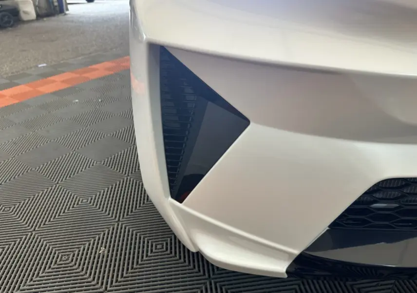 Gros plan sur l’angle avant gauche blanc de l’AIXAM AMBITION 0.5 CROSSOVER PREMIUM avec détail noir triangulaire.