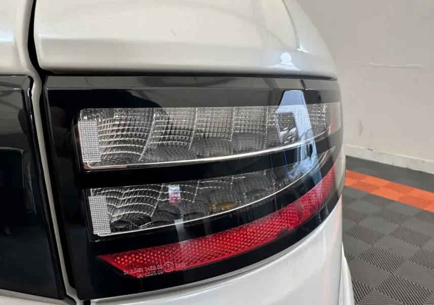 Gros plan sur le feu arrière droit du Aixam Ambition 0.5 Crossover Premium blanc, avec détails noirs et rouges.