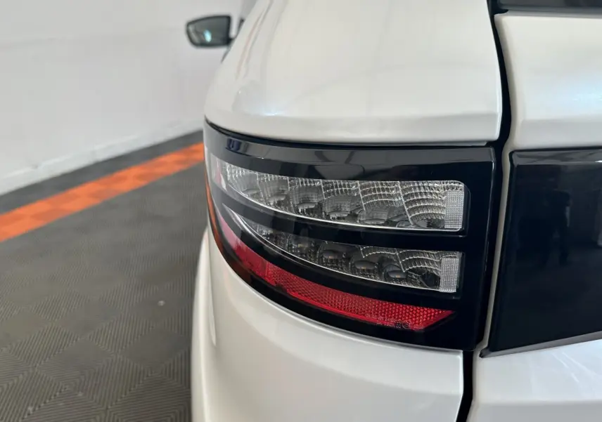 Gros plan sur le feu arrière droit noir et rouge d'une Aixam Ambition 0.5 Crossover Premium blanche, 2026.