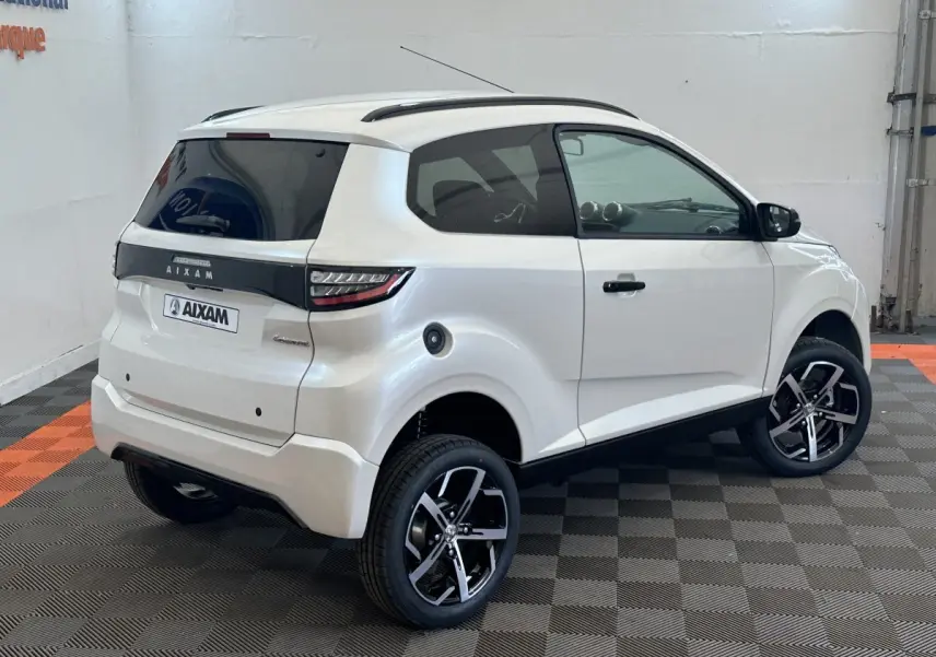 Vue 3/4 arrière droite d'une Aixam Ambition 0.5 Crossover Premium blanche avec rétroviseur caméra côté conducteur.