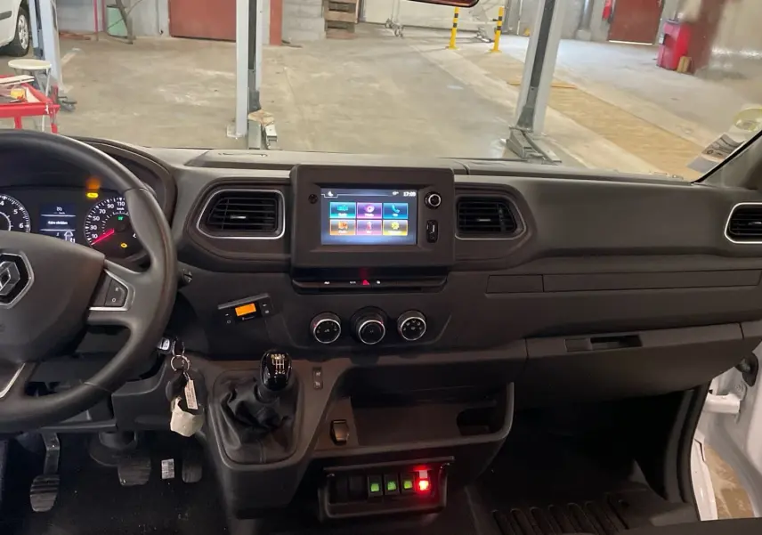 Vue intérieure du tableau de bord du Renault Master blanc, montrant le volant, la boîte manuelle et l’écran tactile central.