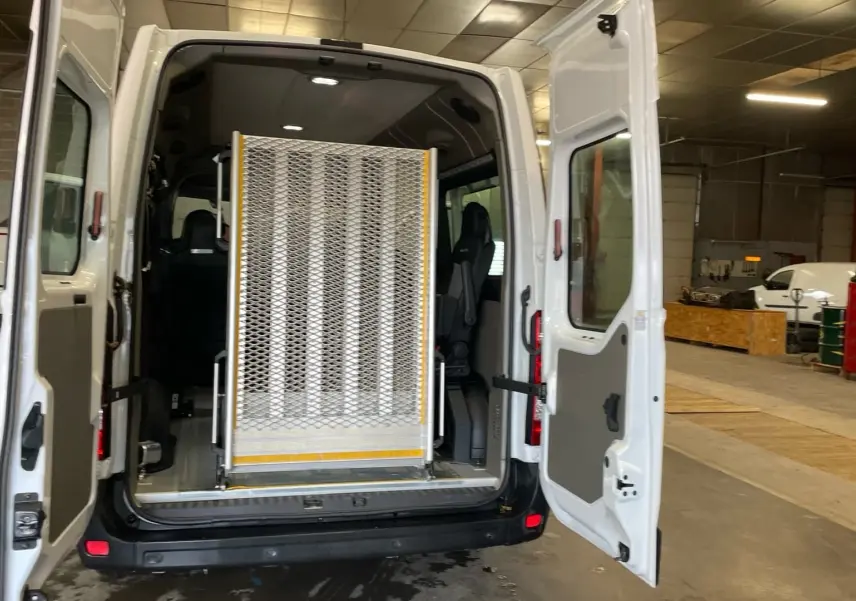 Vue arrière du Renault Master blanc 2020 avec portes ouvertes et rampe d'accès pour fauteuil roulant déployée.