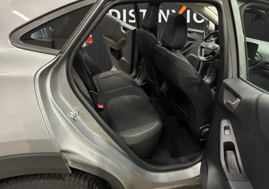 Vue intérieure côté gauche arrière du Ford Puma gris Solar 2023, montrant les sièges arrière et l'avant avec volant multifonction.