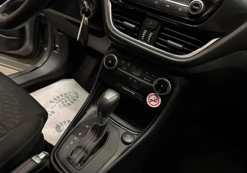 Vue rapprochée de la console centrale intérieure du Ford Puma gris, avec levier de boîte auto et commandes de climatisation.