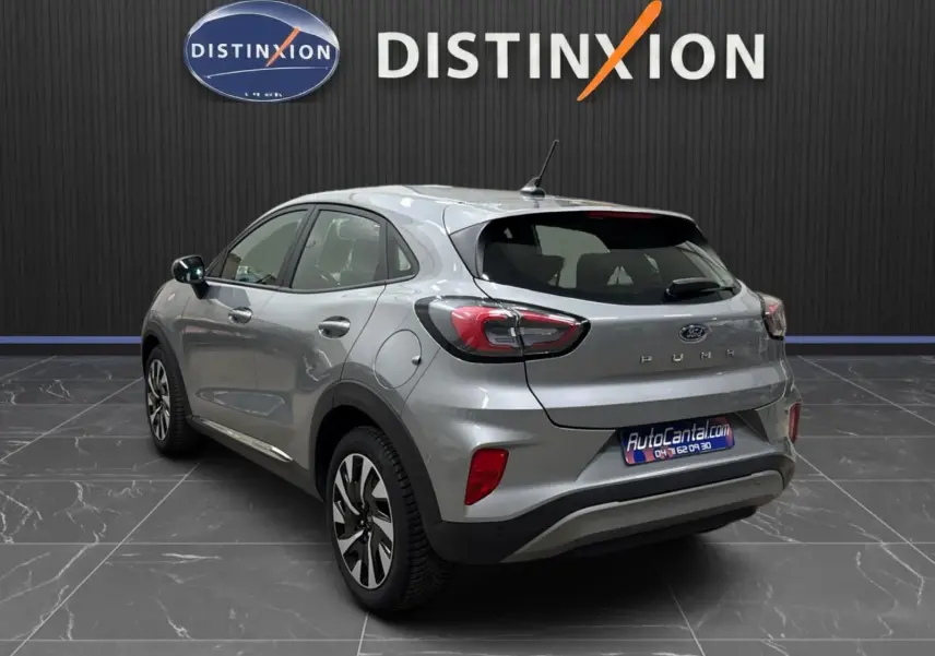 Vue 3/4 arrière droite d'un Ford Puma gris solar 2023 avec feux LED et jantes alliage 17 pouces dans un showroom.