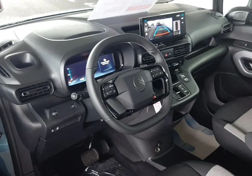 Vue intérieure du poste de conduite du Citroën Berlingo bleu Kiama, avec tableau de bord numérique et écran central tactile.