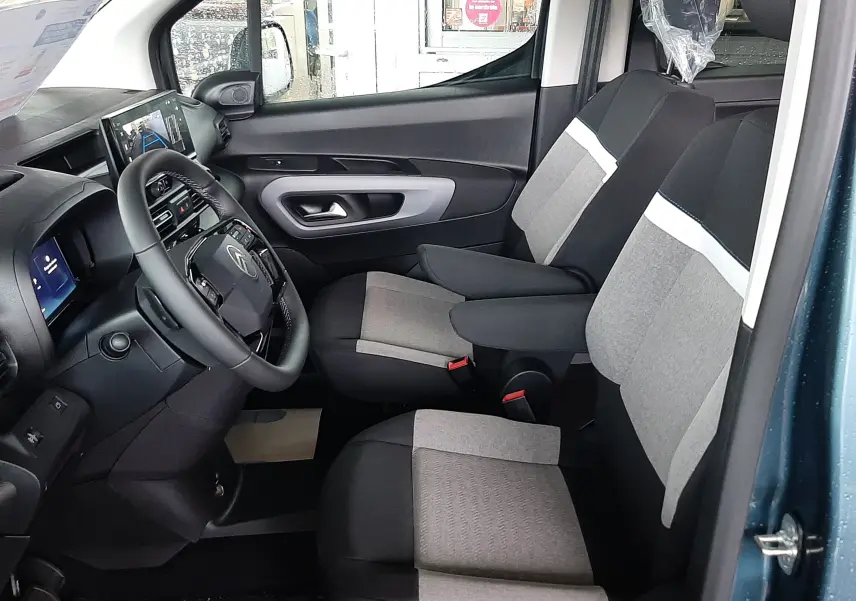 Vue intérieure côté conducteur du Citroën Berlingo bleu Kiama, montrant les sièges tissu gris et noir et le tableau de bord moderne.