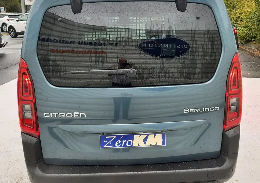 Vue arrière d'un Citroën Berlingo bleu Kiama 2026 avec hayon vitré et feux arrière allumés.
