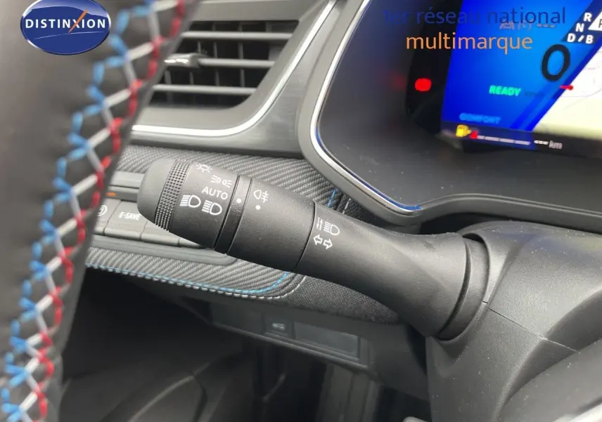 Gros plan sur la commande des phares à gauche du volant avec tableau de bord numérique bleu du Renault Symbioz gris cassiopée.