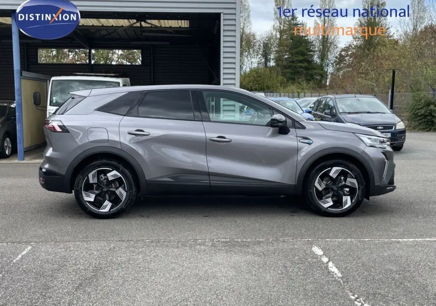 Vue latérale droite du Renault Symbioz gris cassiopée métal 2026, SUV hybride avec jantes stylisées bicolores.