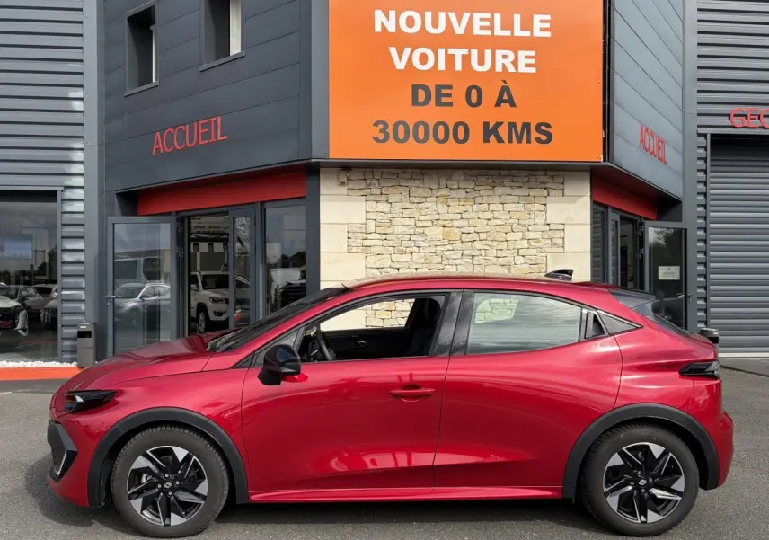Profil côté gauche de la Renault Clio Evolution rouge 2025, hybride essence, avec jantes noires distinctives.