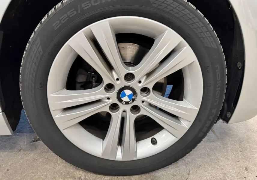Gros plan sur la roue avant gauche avec jante alliage gris et pneu Nokian 225/50 R17 d’une BMW Série 3 Touring F31 gris aluminium.