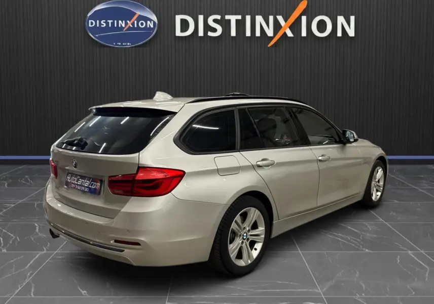 BMW Série 3 Touring gris aluminium vue 3/4 arrière droit, avec attelage électrique et jantes 17 pouces.