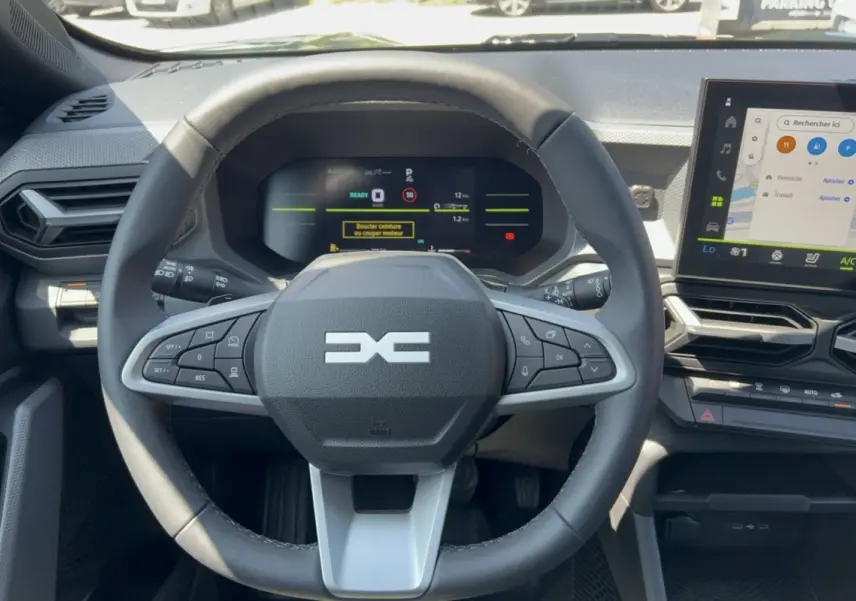 Vue intérieure centrée sur le volant cuir et le tableau de bord numérique du Dacia Duster Hybrid-G 2026.