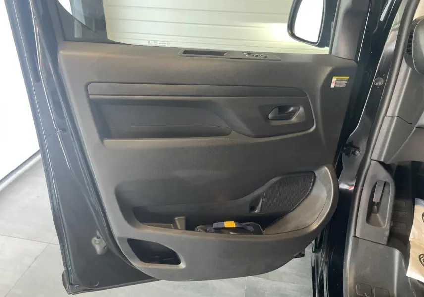 Vue rapprochée de la porte avant gauche noire carbone de l'Opel Vivaro 2025 avec poignée et rangement intégré.