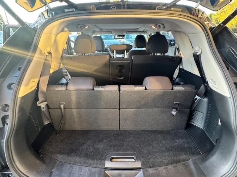 Vue arrière ouverte du coffre du Nissan X-TRAIL noir intense 2018, montrant les sièges 7 places en tissu graphite.