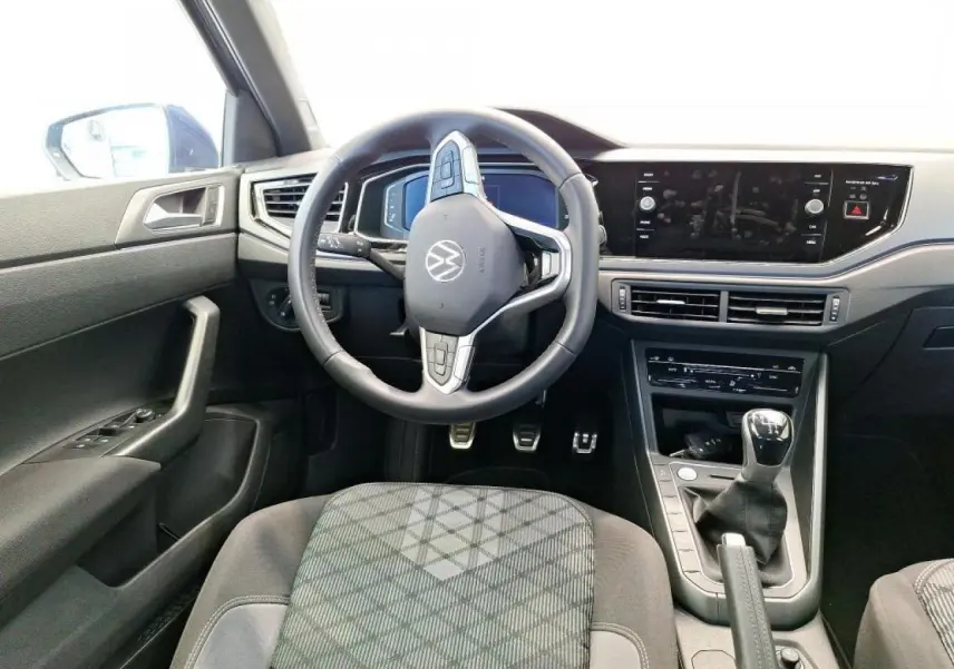Vue intérieure frontale du poste de conduite de la Volkswagen Polo TSI 95 R-Line 2024 avec volant cuir multifonction et levier de vitesses manuel.