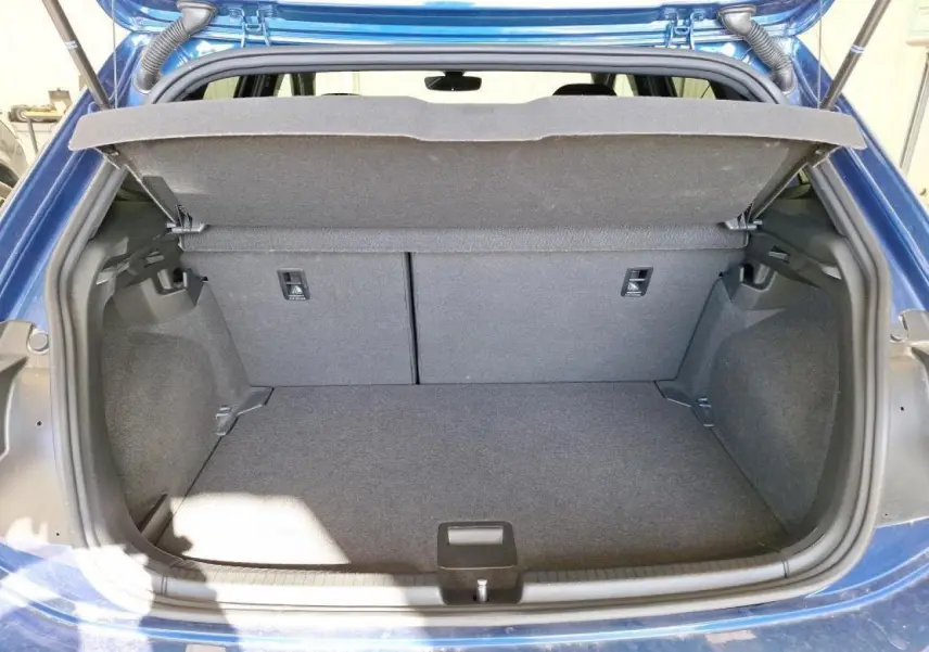 Coffre ouvert vu de l'arrière d'une Volkswagen Polo TSI 95 R-Line bleu récif avec espace de chargement vide.