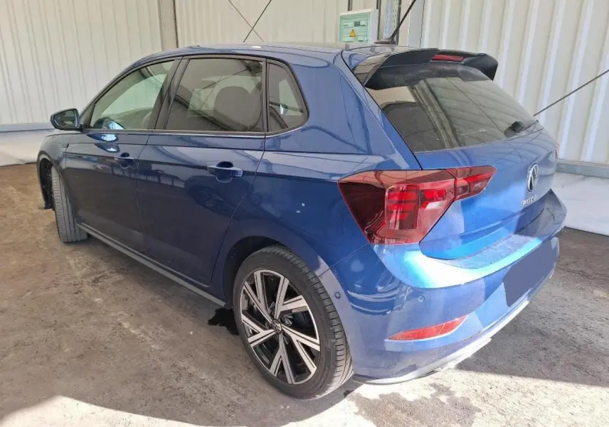 Vue 3/4 arrière droite d'une Volkswagen Polo TSI 95 R-Line bleu récif avec jantes alliage 17 pouces et vitres surteintées.