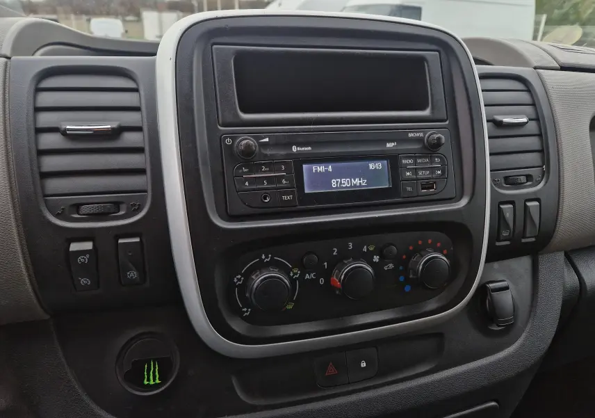 Tableau de bord du Renault Trafic Fourgon blanc, vue centrale sur la radio et les commandes de climatisation.