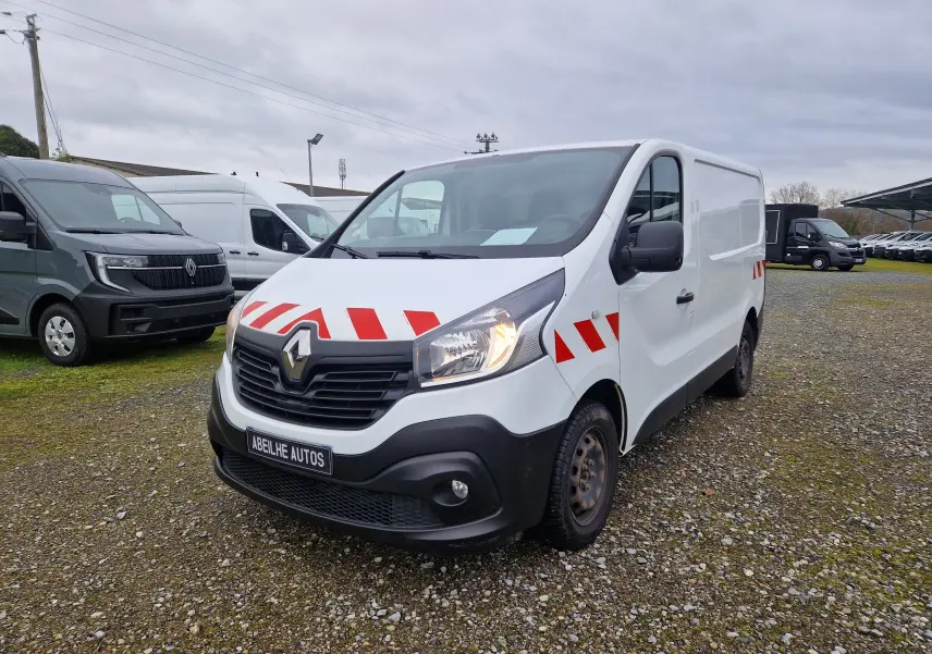Vue 3/4 avant d’un Renault Trafic fourgon blanc 2019 avec bandes rouges réfléchissantes sur capot et portières.