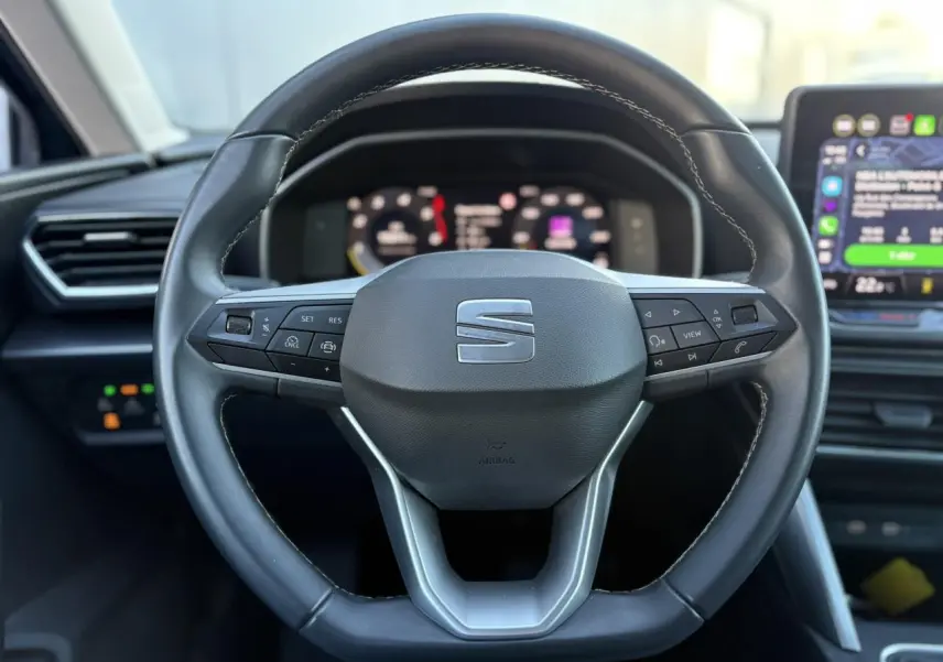 Volant cuir multifonction noir de la SEAT LEON ST 2.0 TDI 115 Style avec tableau de bord numérique en arrière-plan flou.