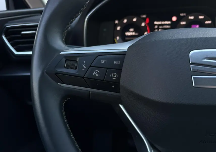 Gros plan sur le volant cuir multifonction de la SEAT LEON ST 2.0 TDI 115 Style avec commandes de régulateur de vitesse.