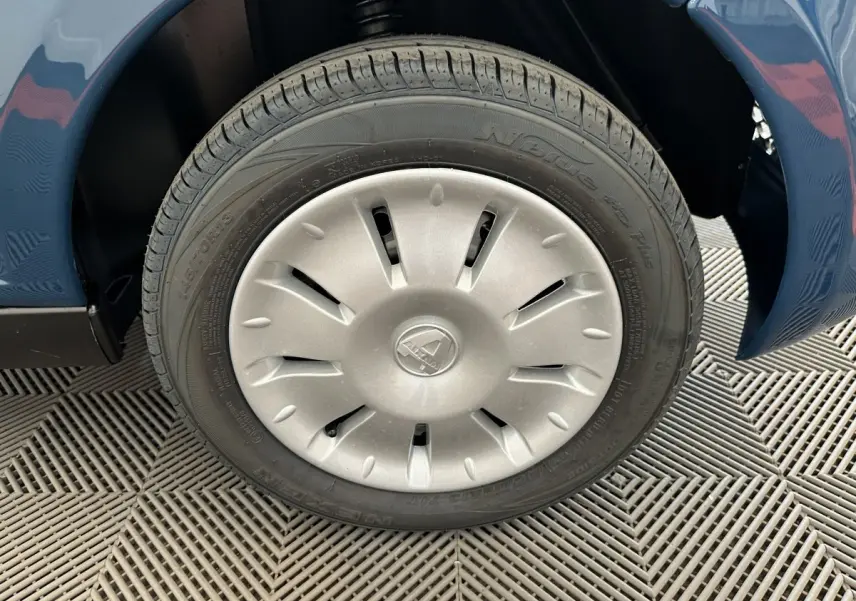 Gros plan sur la roue avant gauche de l'AIXAM AMBITION 0.5 CITY PACK bleu avec enjoliveur argenté.