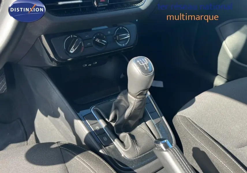 Gros plan sur la console centrale d’une Skoda Fabia noire, avec levier de vitesse manuel et commandes de climatisation.