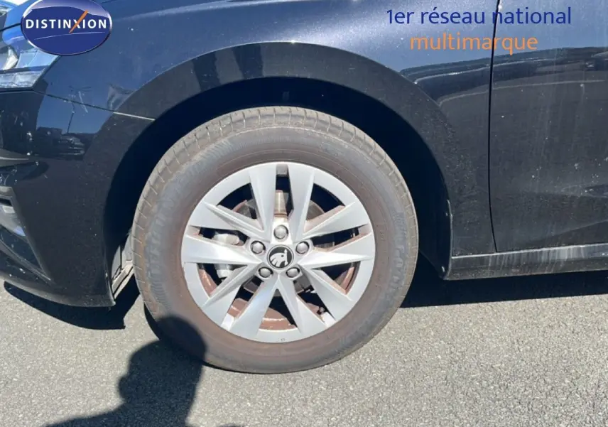 Gros plan sur la roue avant gauche d'une Skoda Fabia noire métal, mettant en valeur la jante en alliage et le logo central.