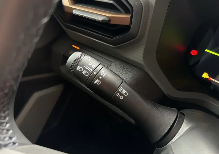 Gros plan sur la commande des feux et clignotants à gauche du volant dans l’habitacle du Dacia Bigster Hybrid 155 Extreme.