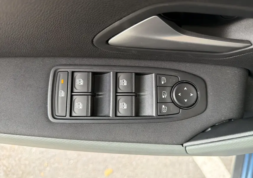 Gros plan sur les commandes des vitres et rétroviseurs côté conducteur du Dacia Bigster Hybrid 155 Extreme bleu indigo.