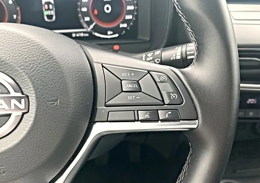 Gros plan sur le volant cuir noir du Nissan Juke 2025, montrant les commandes multifonctions côté droit.