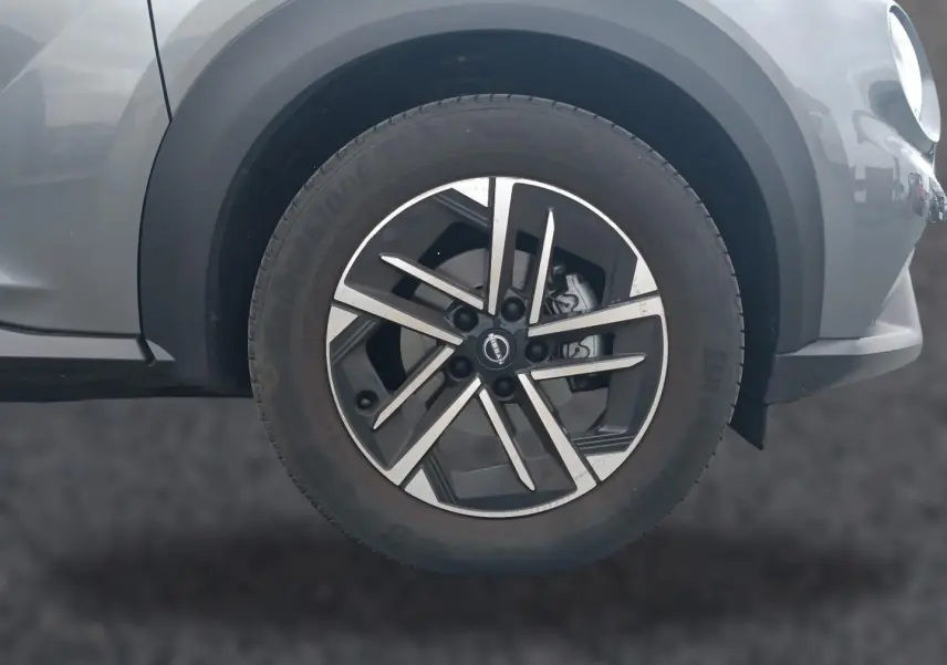 Gros plan sur la roue avant gauche du Nissan Juke gris 2025 avec jante alu au design moderne à branches croisées.