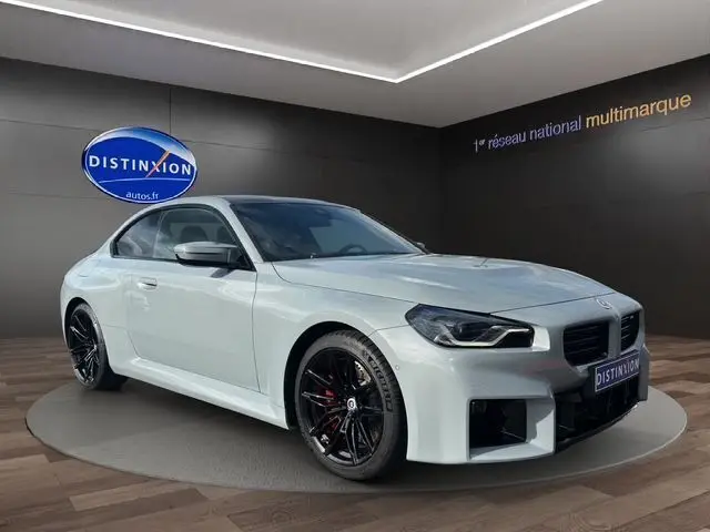 BMW M2 G87 gris Brooklyn en 3/4 avant droit, jantes noires et détails sportifs en showroom Distinxion.