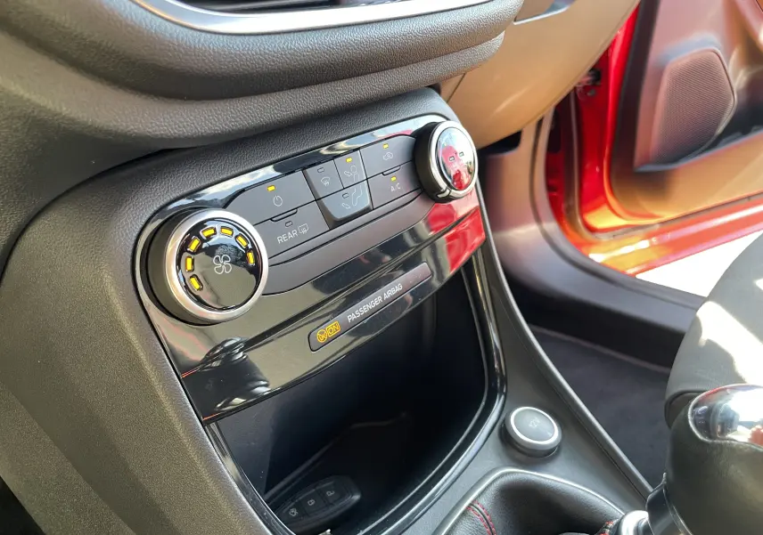 Vue rapprochée de la console centrale du Ford Puma rouge 2021, mettant en valeur les commandes de climatisation et la boîte manuelle.