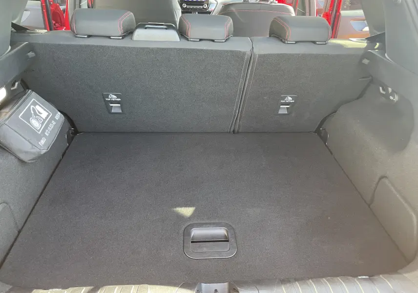 Coffre ouvert d'un Ford Puma rouge 2021, vue intérieure arrière montrant banquette arrière et espace de chargement noir.