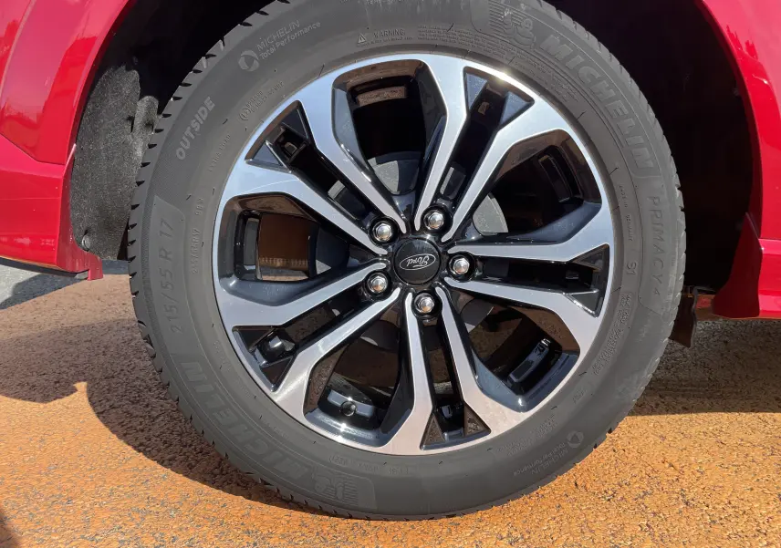 Gros plan sur la roue avant gauche d'un Ford Puma rouge avec jante alliage bicolore et pneu Michelin.