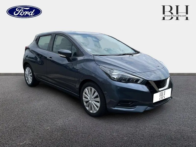 Vue 3/4 avant droit d'une Nissan Micra gris acier avec phares anguleux et jantes alliage simples.