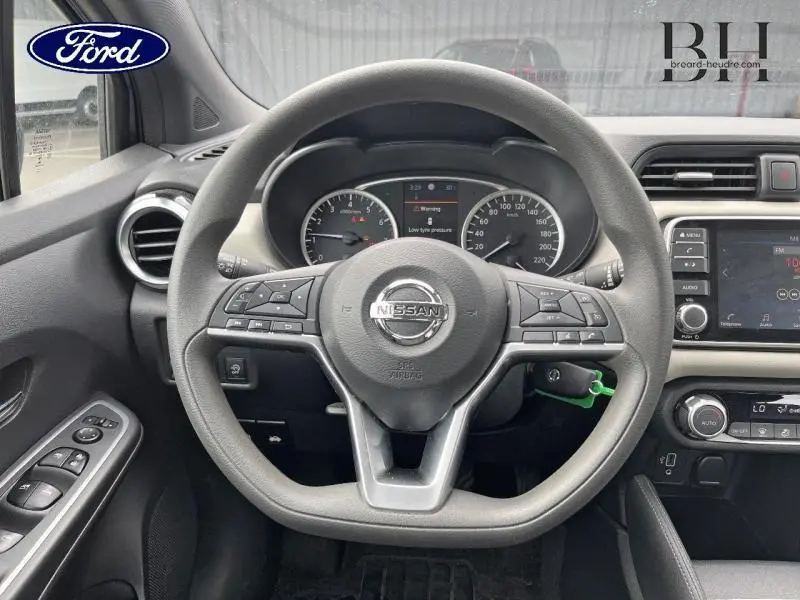 Vue intérieure centrée sur le volant Nissan gris avec tableau de bord et écran tactile, détails du poste de conduite.