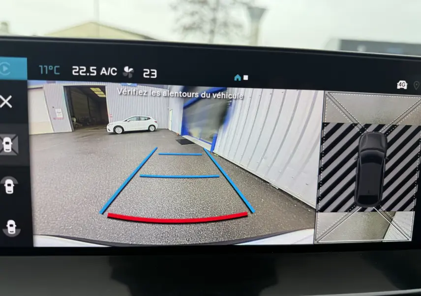 Vue caméra de recul d'une Citroën C4 Hybrid 145 blanc Okenite, avec lignes de guidage bleues et rouges visibles.