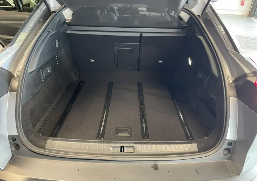 Vue arrière du coffre ouvert d'une Citroën C5 X gris foncé 2024, montrant un espace de chargement spacieux et bien fini.