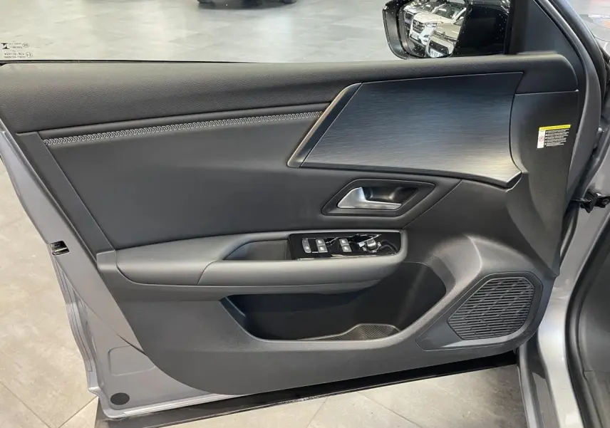 Vue intérieure côté gauche de la porte avant gris foncé du Citroën C5 X 2024 avec commandes de vitres et finition moderne.